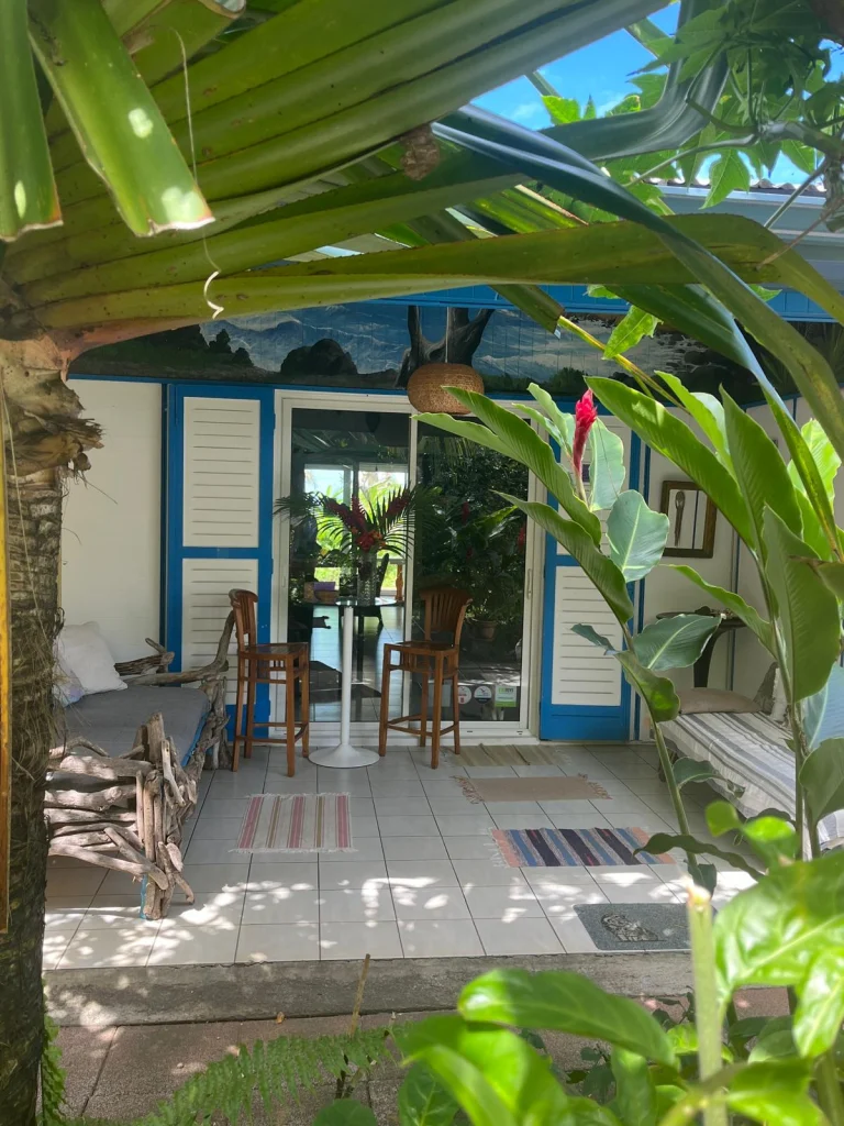 La véranda : volets bleus, banquettes en bois flotté et jardin tropical