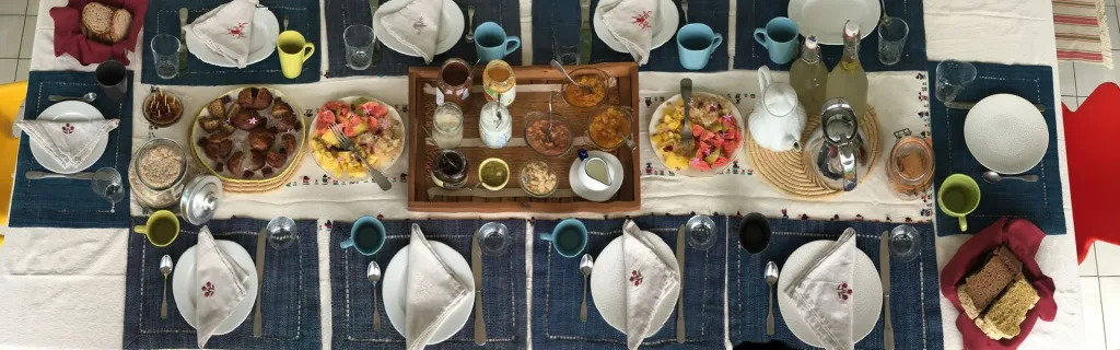 La table du petit-déjeuner : fruits frais, pains et confitures maison